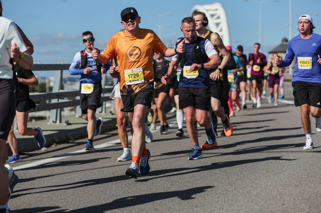 A group of runners participating in a race on a sunny day, wearing race bibs and athletic gear.